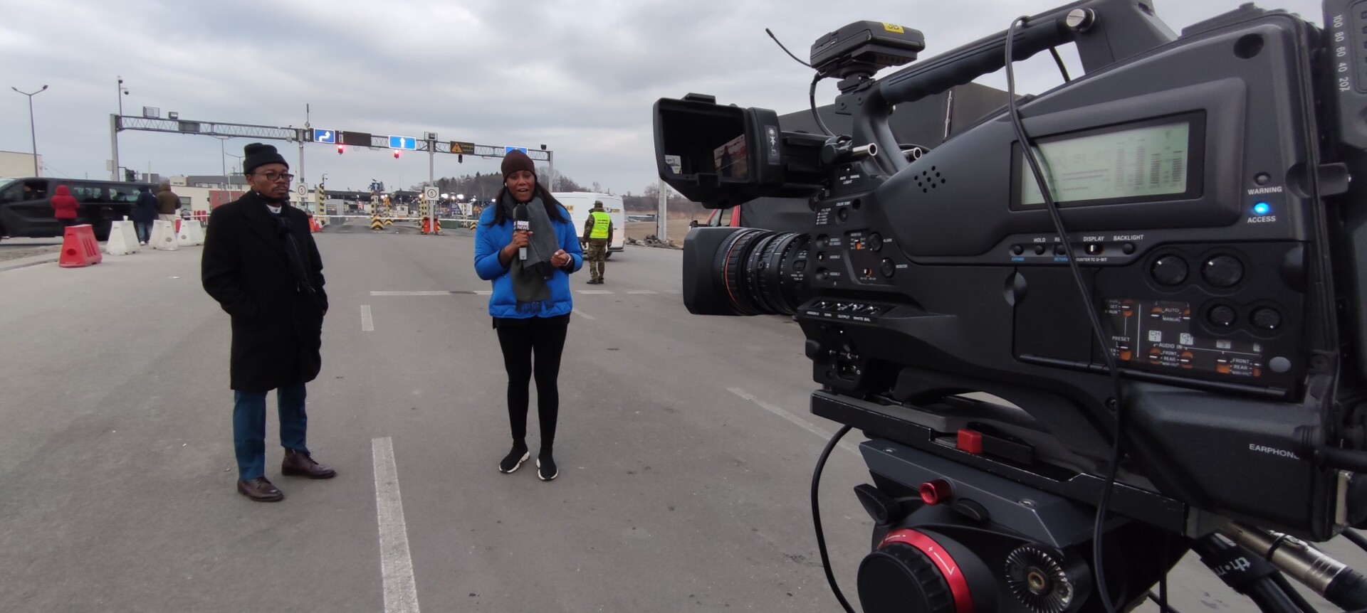 Reporter and broadcast camera crew recording a live stand-up report in the field